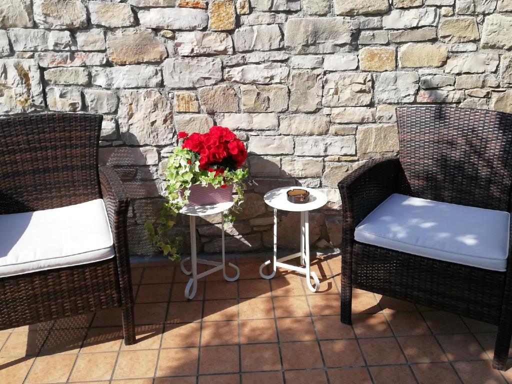 エルブスコにあるACERO ROSSO B&B in Franciacortaの赤い花のテーブルと椅子2脚付きのパティオ