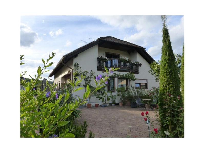 een wit huis met een balkon en bloemen bij Ferienwohnung Schillinger in Sasbach am Kaiserstuhl