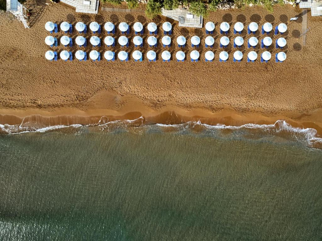 una vista aérea de una playa con una fila de taburetes en Giannoulis – Santa Marina Beach Hotel en Agia Marina Nea Kydonias