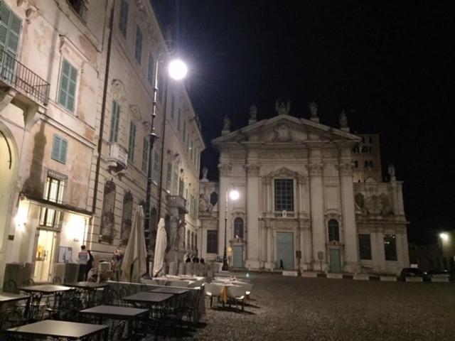 マントヴァにあるPalazzo Guerrieri da Fermoの夜間の建物の前にテーブルと椅子がある建物