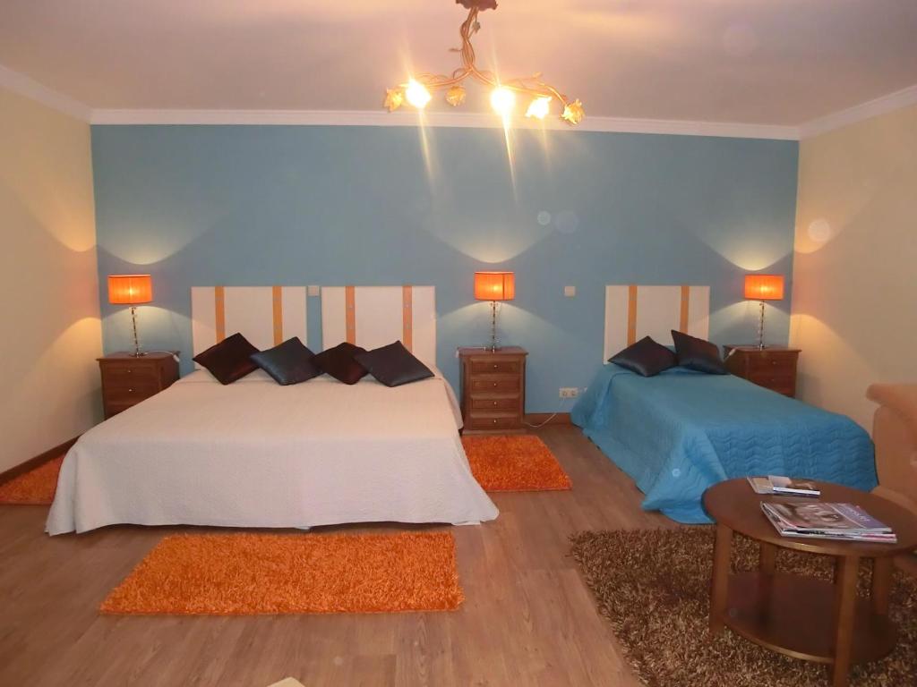 a bedroom with two beds and a blue wall at Solar de Rabal in Bragança