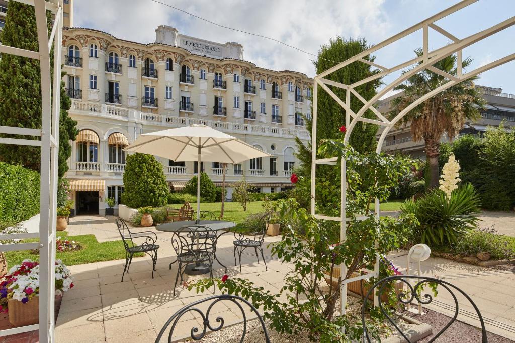 une cour avec une table et des chaises et un bâtiment dans l'établissement Residence Vacances Bleues le Mediterranée, à Saint-Raphaël
