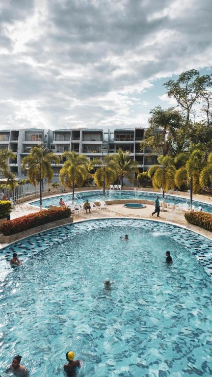 a large swimming pool with people in the water at Condominio Terrazas del Sol in Sopetrán
