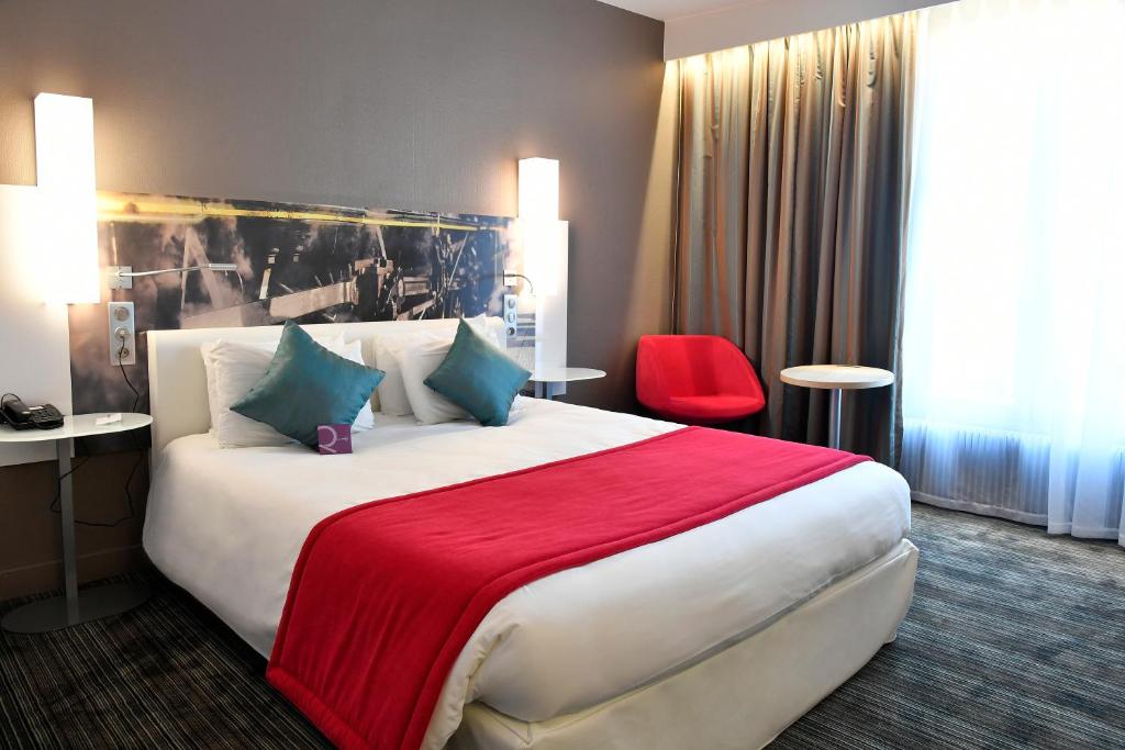 a hotel room with a large bed with a red blanket at Mercure Paris Gare de l'Est in Paris
