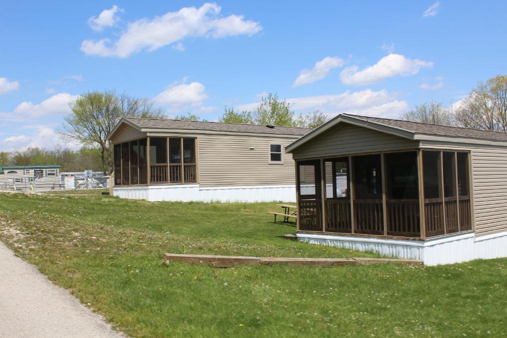 un edificio con porche en un campo de césped en Plymouth Rock Camping Resort Two-Bedroom Park Model 9, en Elkhart Lake