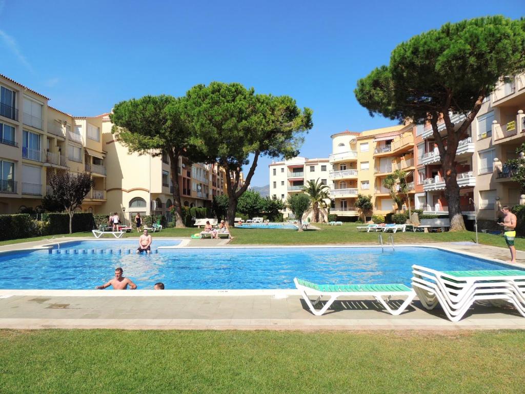 a swimming pool with two lawn chairs and some buildings at Flores 19 12 Empuriabrava Gran Reserva - Immo Barneda in Empuriabrava