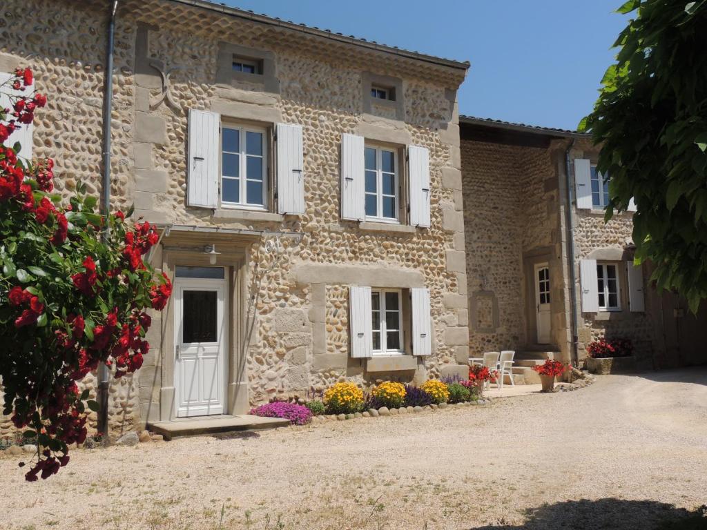 uma casa de pedra com flores em frente em La Ferme des Buis em Mercurol