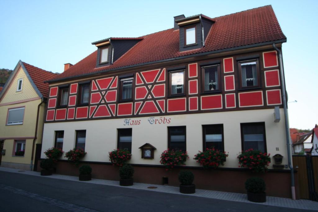 ein rot-weißes Gebäude mit Blumen davor in der Unterkunft Gästehaus Tröbs in Ilfeld