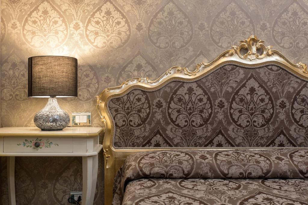 een slaapkamer met een bed en een tafel met een lamp bij Hotel Mezzo Pozzo in Venetië