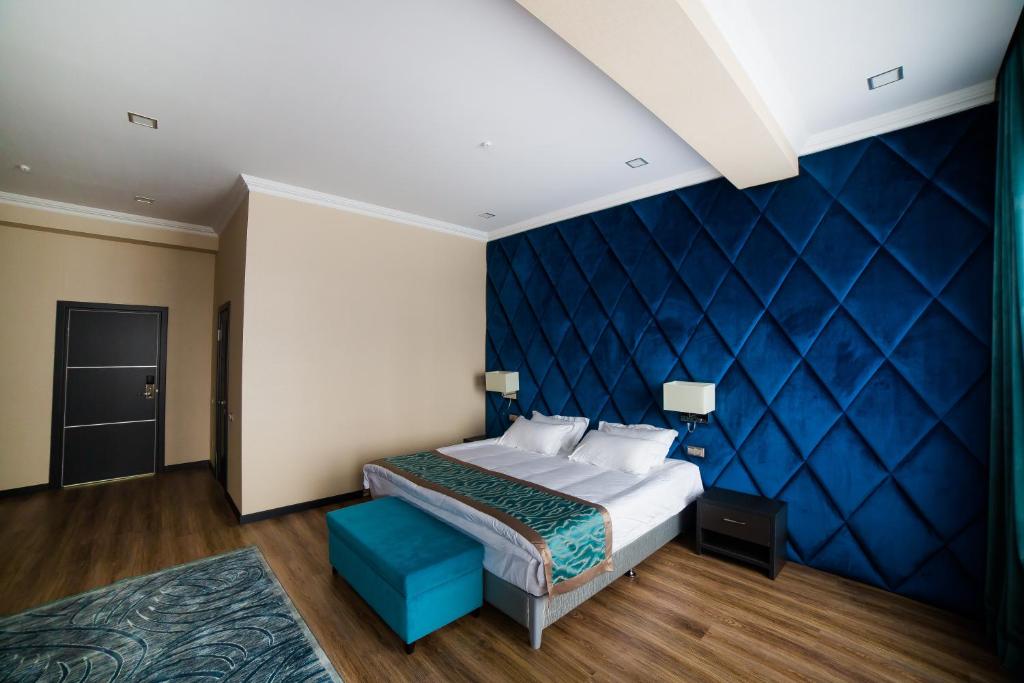 ein Schlafzimmer mit einem Bett und einer blauen Wand in der Unterkunft Golden Hotel in Bischkek