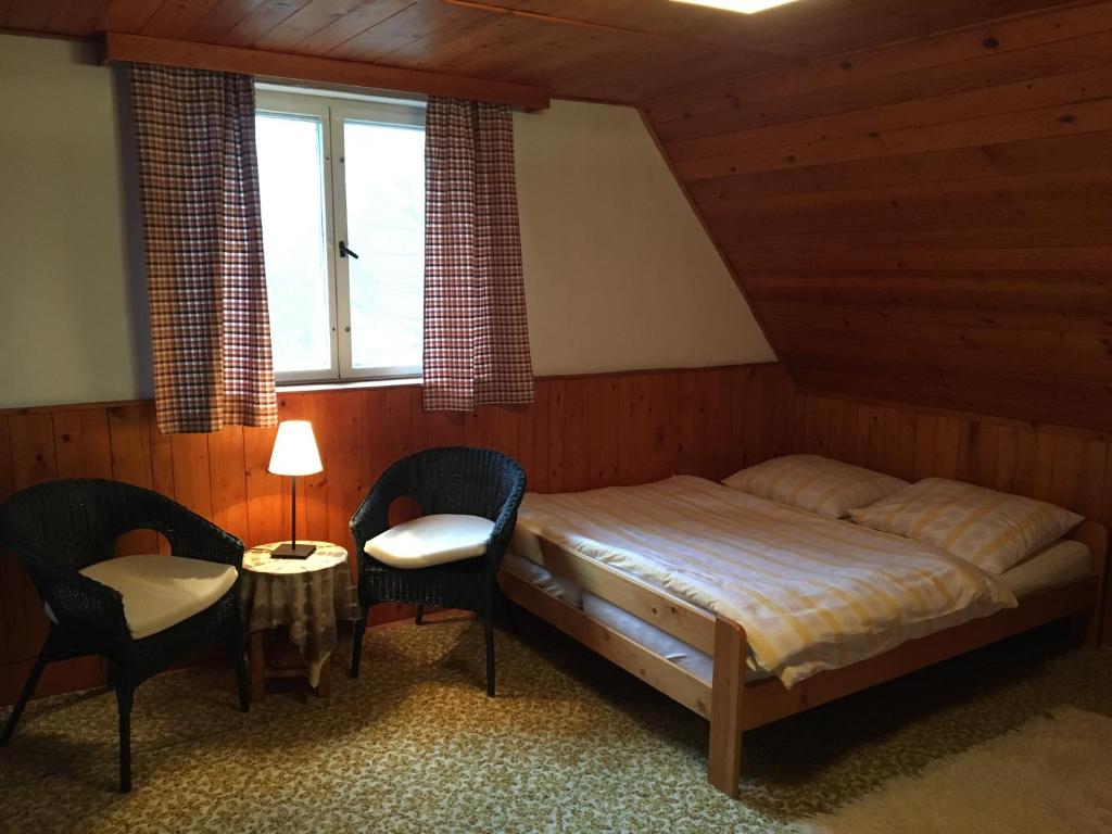 a bedroom with a bed and chairs and a window at Chata u koupaliště in Chřibská