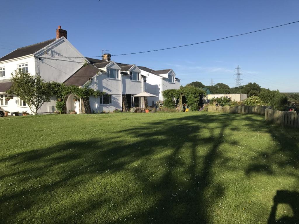 una casa grande en un patio con una gran sombra en Brynawel Farm B&B, en Pontlliw