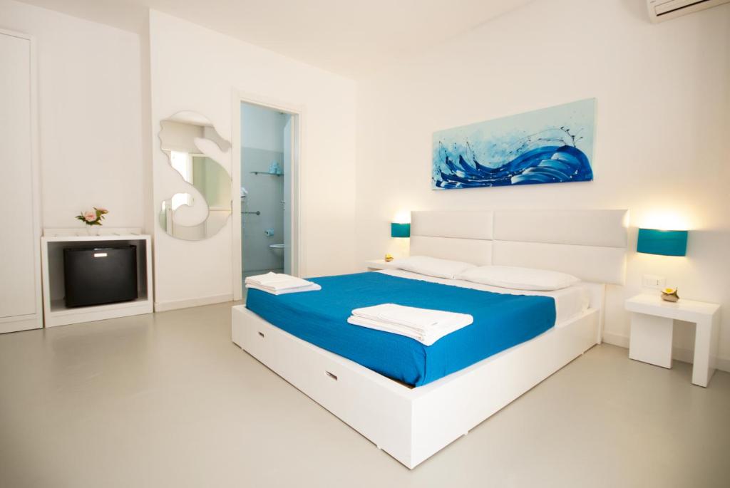 Habitación blanca con cama azul y TV. en Hotel Beach Salento en Marina di Pescoluse
