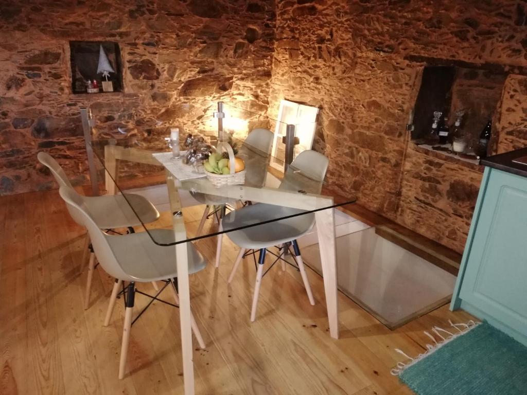 Casinha do Talasnal في لوسا: غرفة طعام مع طاولة وكراسي زجاجية