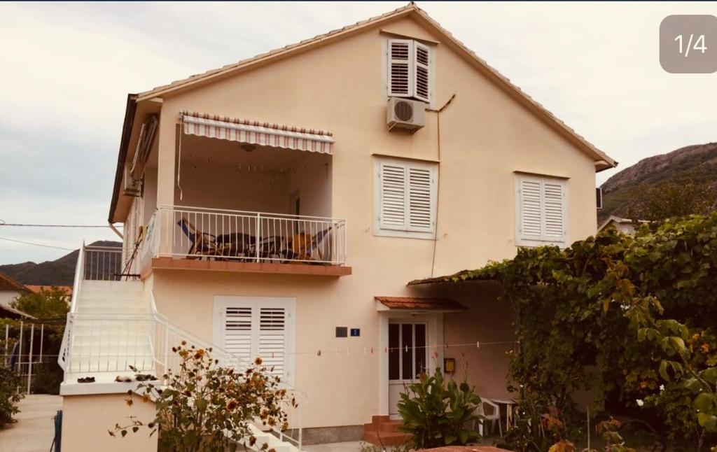 une maison blanche dotée d'un balcon avec deux chiens. dans l'établissement Anita Guest House, à Tivat