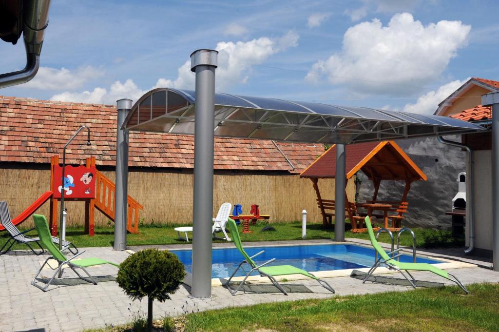 ein Baldachin über einem Pool mit Stühlen und einem Spielplatz in der Unterkunft Arany Szőlő Wellness Apartmanház in Hévíz