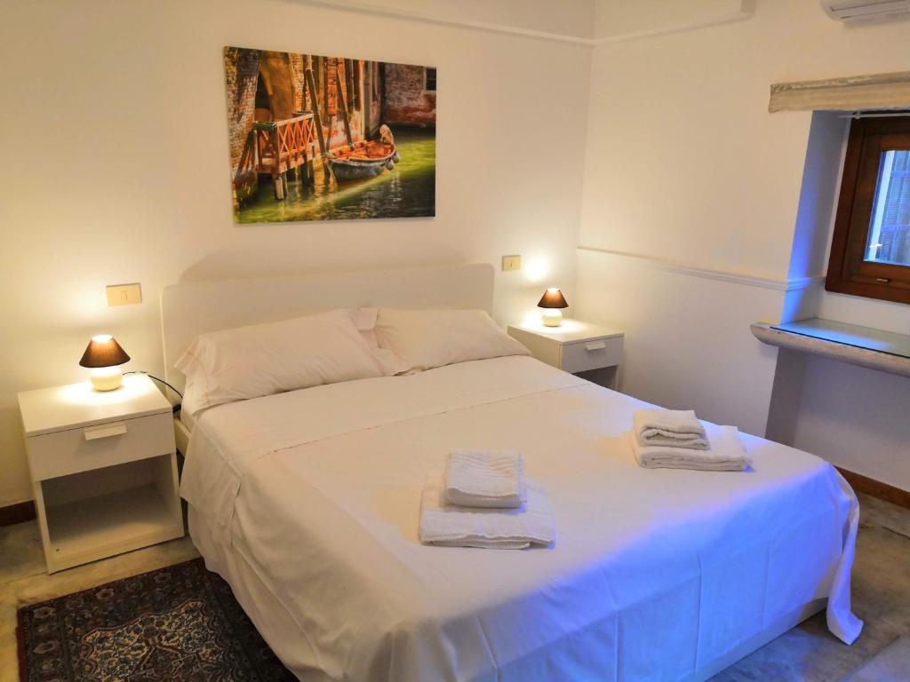 ein Schlafzimmer mit einem weißen Bett mit zwei Handtüchern darauf in der Unterkunft CASTELLO Ground Floor in Venedig