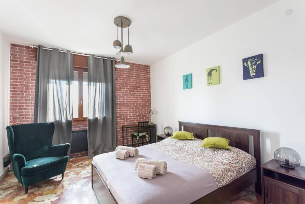 a bedroom with a bed and a green chair at La Serenissima - A charming and quirky experience in Campalto