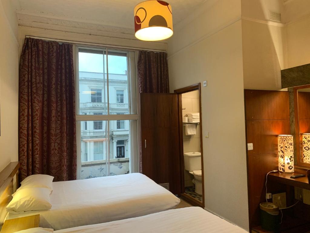 a hotel room with two beds and a window at London Visitors Hotel in London