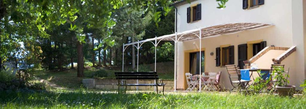 ein Haus mit einer Veranda und einer Bank im Hof in der Unterkunft Il Casale Di Montefreddo in Sirolo