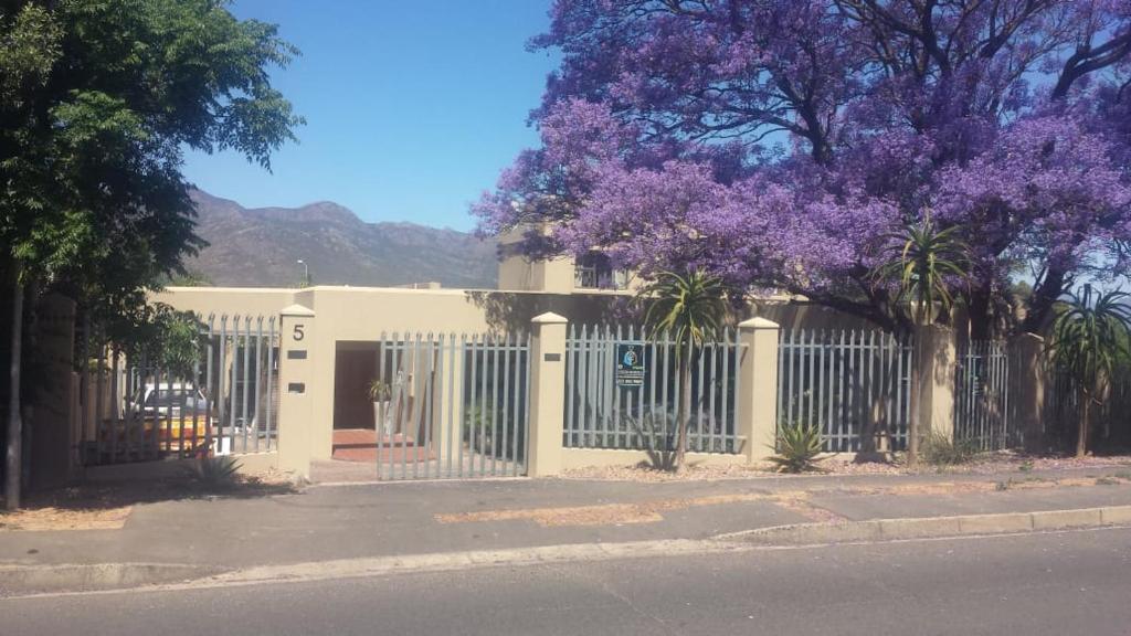 een wit hek met een paarse bloeiende boom erachter bij 5 on Pieter Hugo in Paarl