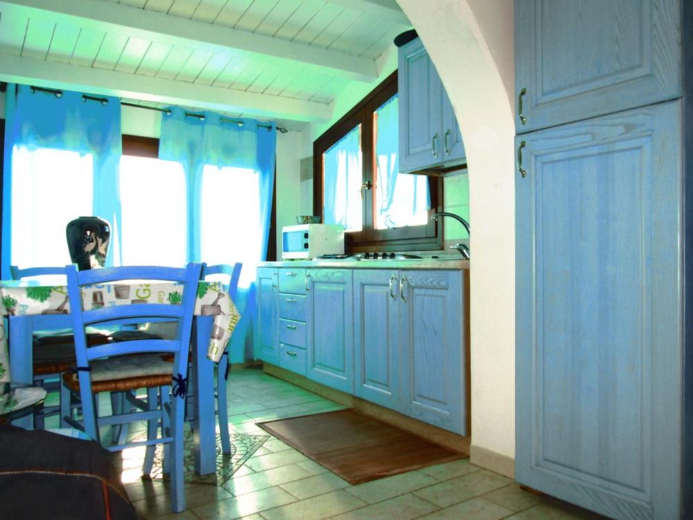 a kitchen with blue cabinets and a table and chairs at Sardinia Yellow House in Solanas