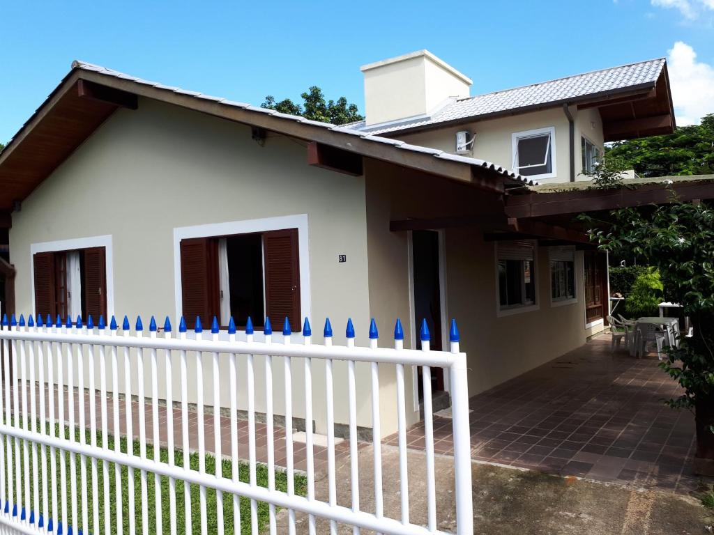 una cerca blanca frente a una casa en Monsal Casa para Temporada, en Florianópolis