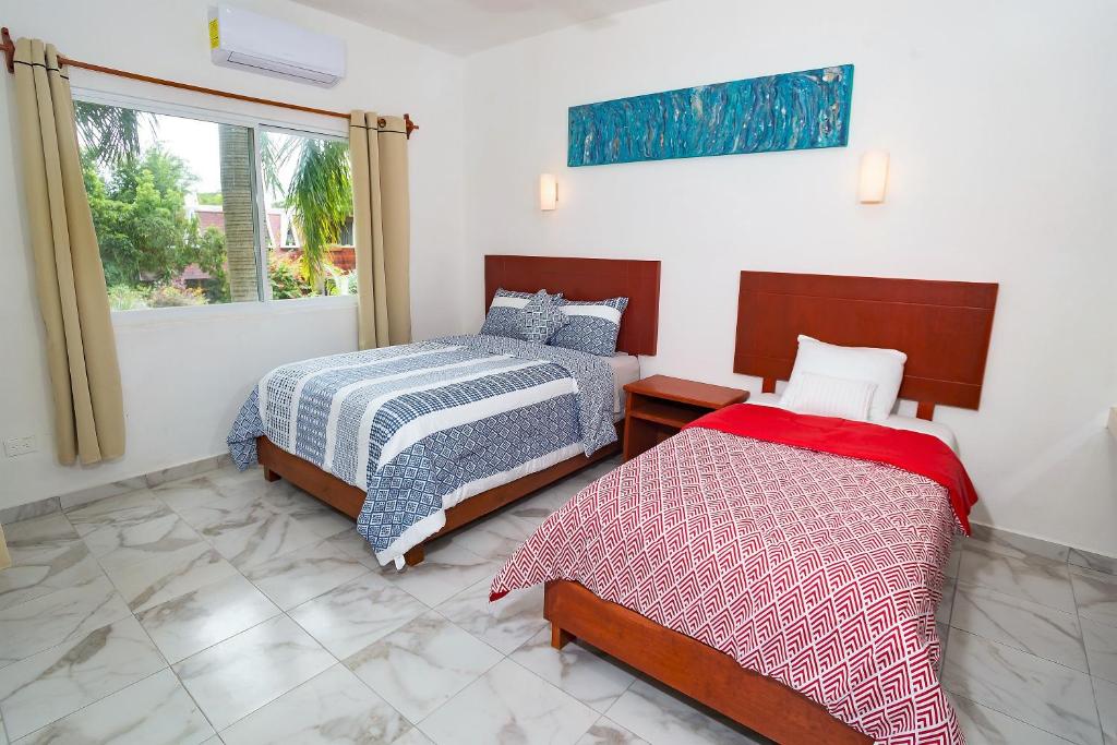 ein Schlafzimmer mit zwei Betten und einem Fenster in der Unterkunft Villa Alebrije Cozumel in Cozumel