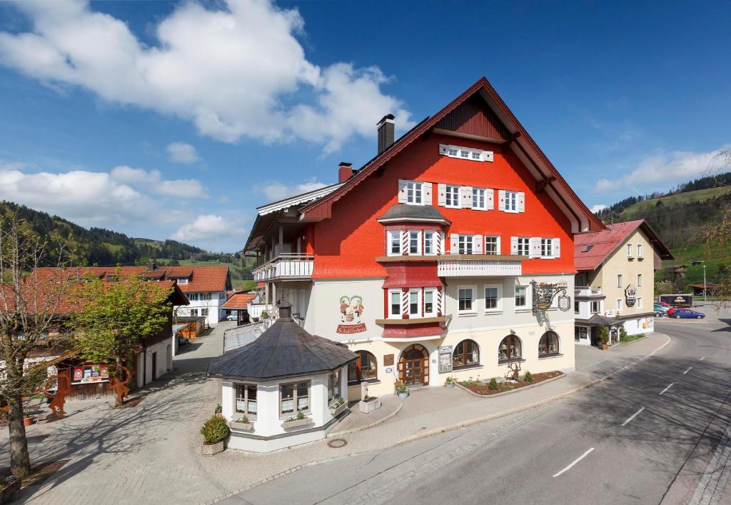 un grand bâtiment orange et blanc dans une ville dans l'établissement Brauereigasthof Schäffler, à Missen-Wilhams