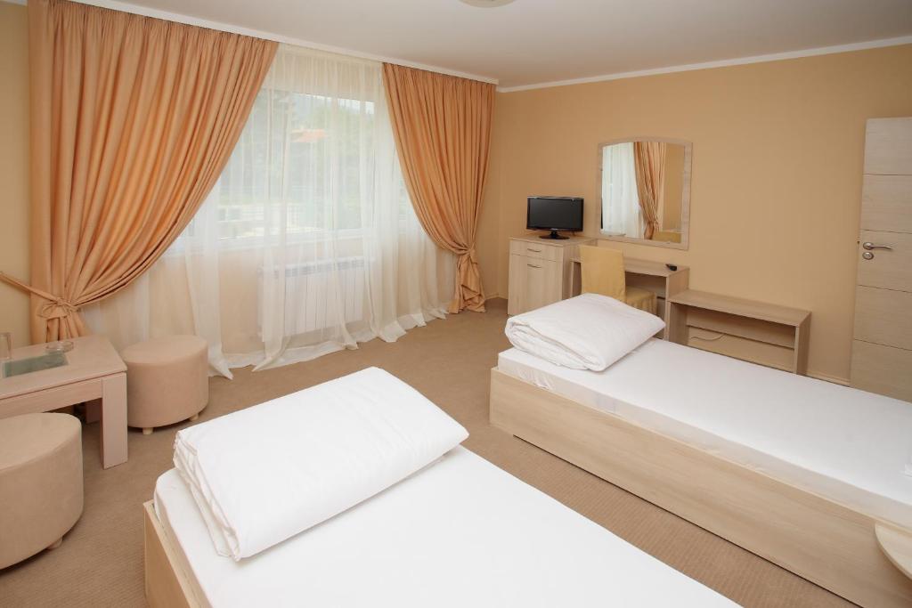 a bedroom with two beds and a desk and a window at Family Hotel Diana in Sofia