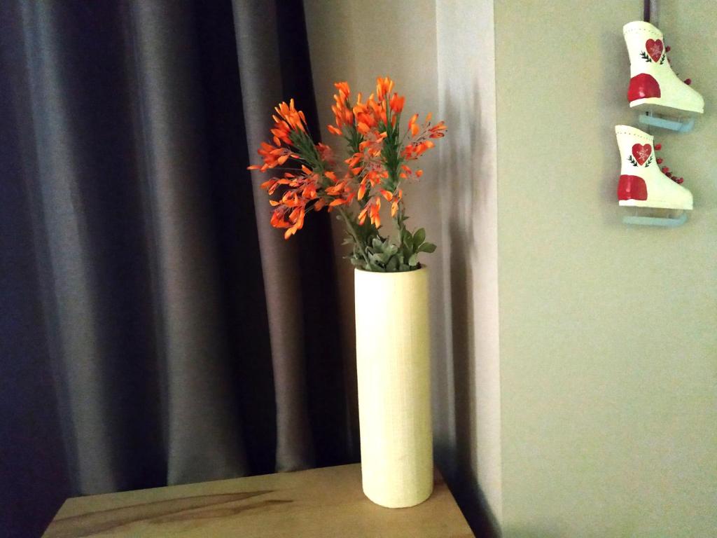eine weiße Vase mit orangefarbenen Blumen auf einem Tisch in der Unterkunft Parnassiko Guest House in Arachova