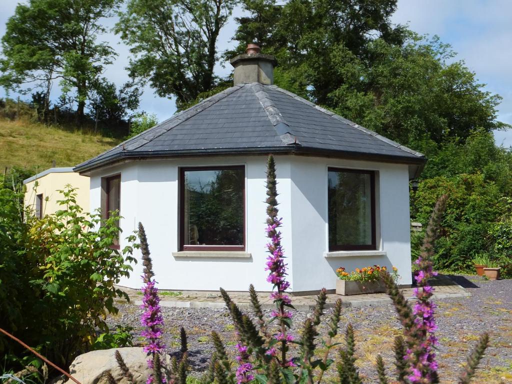 a small white house with a black roof at Drombrow Cottage in Bantry