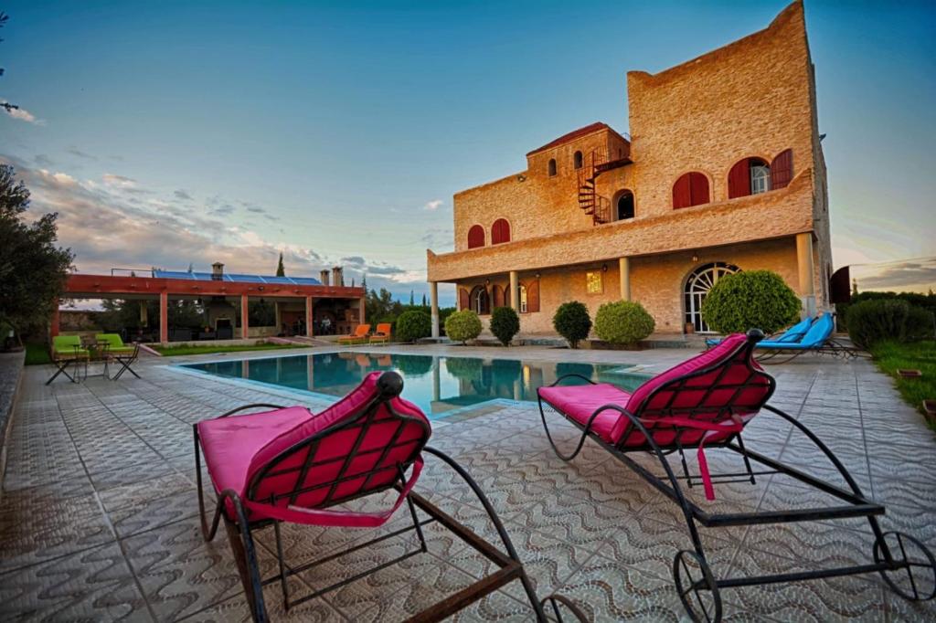 two pink chairs sitting next to a swimming pool at Villa Al Jaouhara in Essaouira