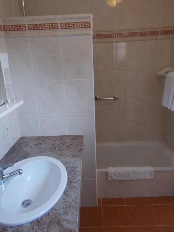 a bathroom with a sink and a bath tub at Hotel Manitoba in Blankenberge