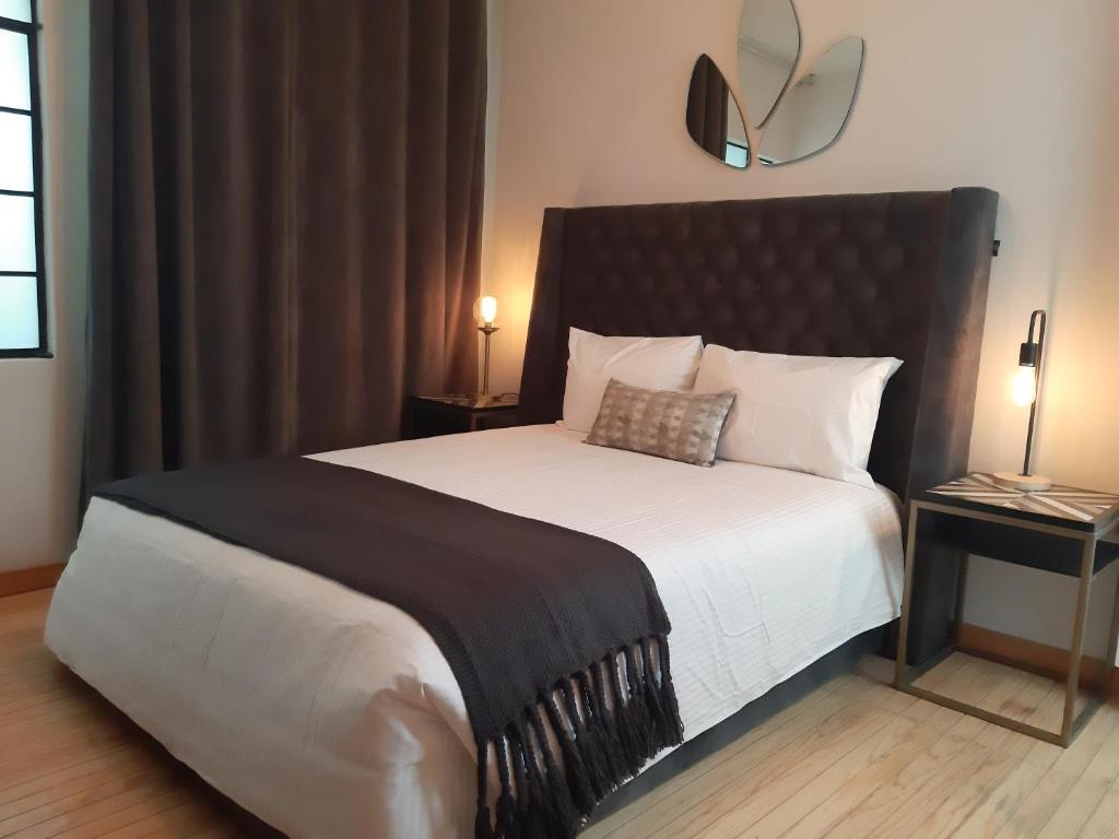 Suites Alcazar في مدينة ميكسيكو: غرفة نوم مع سرير كبير مع اللوح الأمامي الأسود