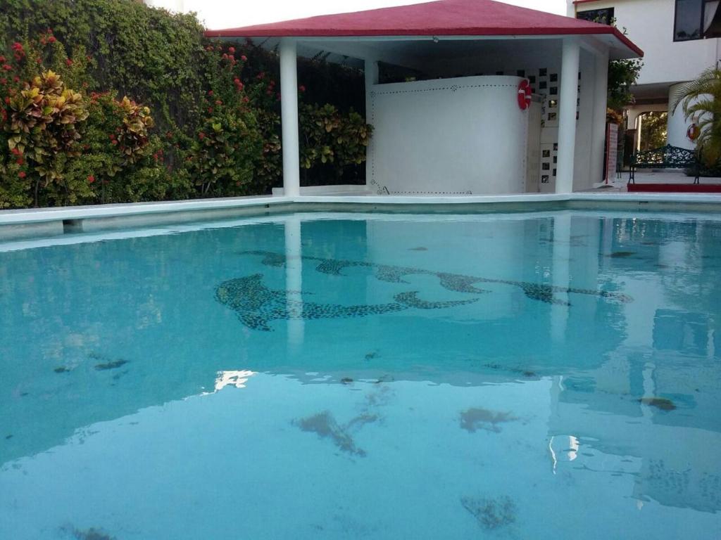 uma grande piscina de água azul em frente a uma casa em Balcon Gueela em Santa Cruz, Huatulco