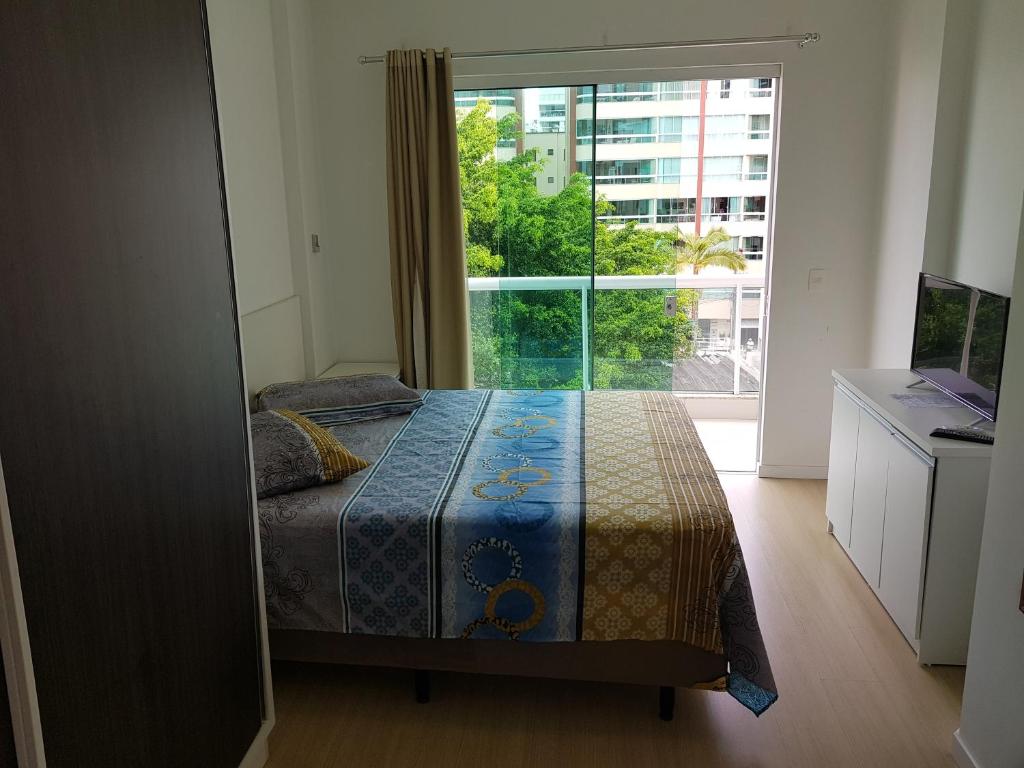 a bedroom with a bed and a large window at Residencial Neli Passos in Itapema