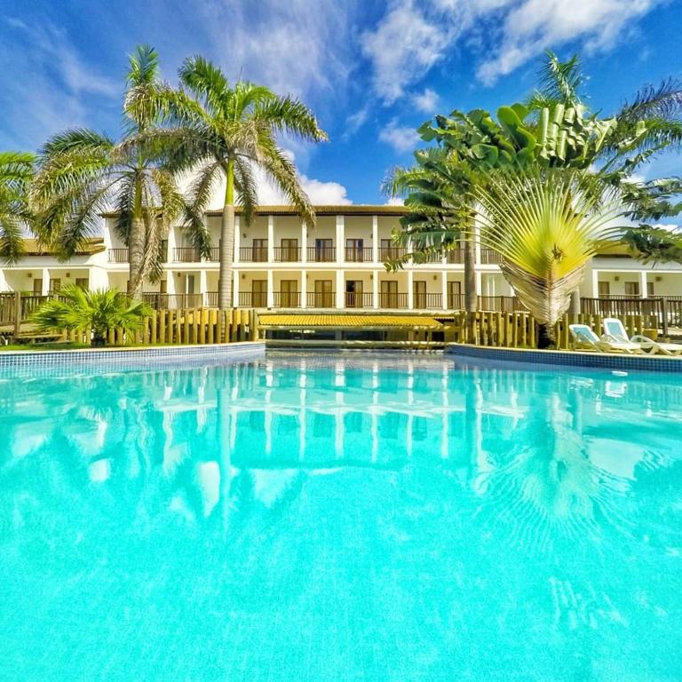a large swimming pool in front of a building with palm trees at Apartamento 3 Quartos Tree Bies Resort Subauma in Subaúma