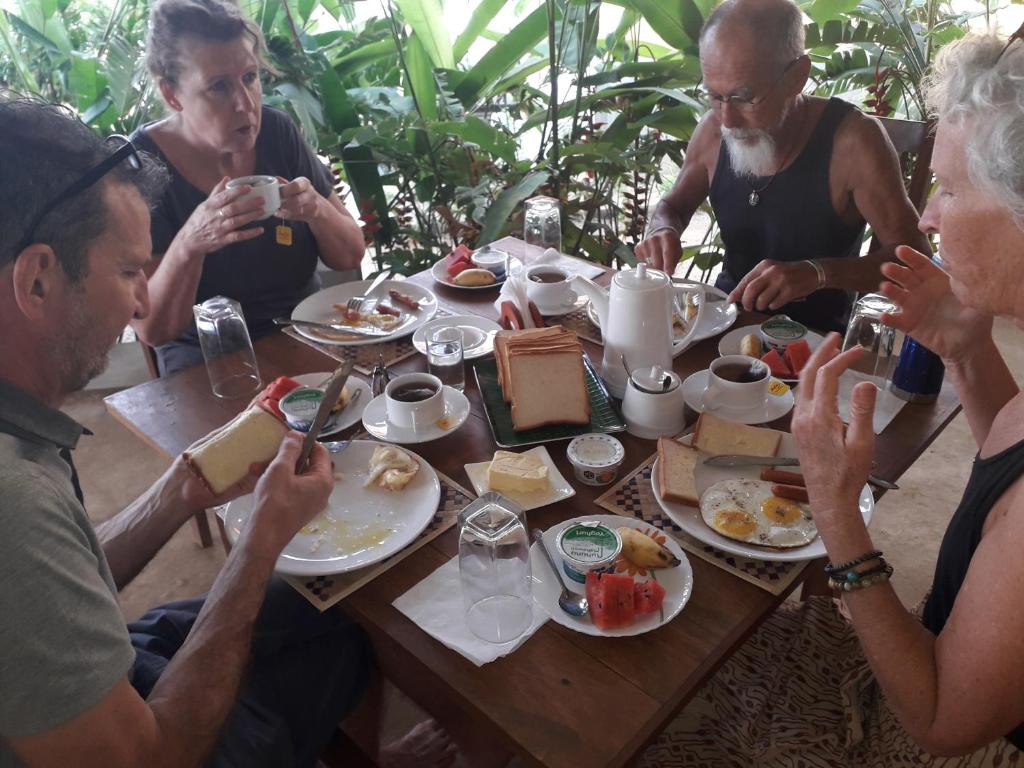 grupa ludzi siedzących przy stole jedzących jedzenie w obiekcie Great Lake Villa w mieście Tissamaharama