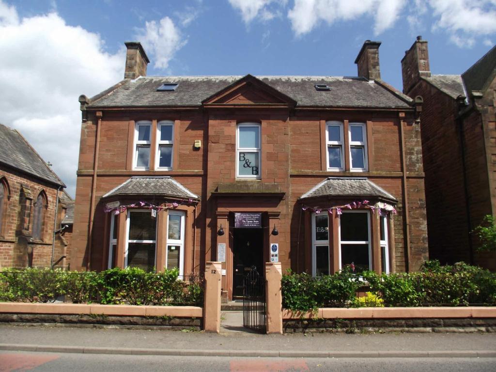 un viejo edificio de ladrillo con una puerta delante de él en The Old Rectory, en Annan