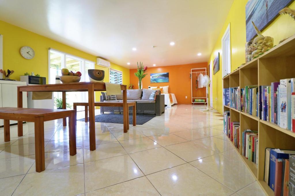 a living room with bookshelves and a dining room at ShineAwayHomes - Mountain View AIR CONDITIONED in Rarotonga