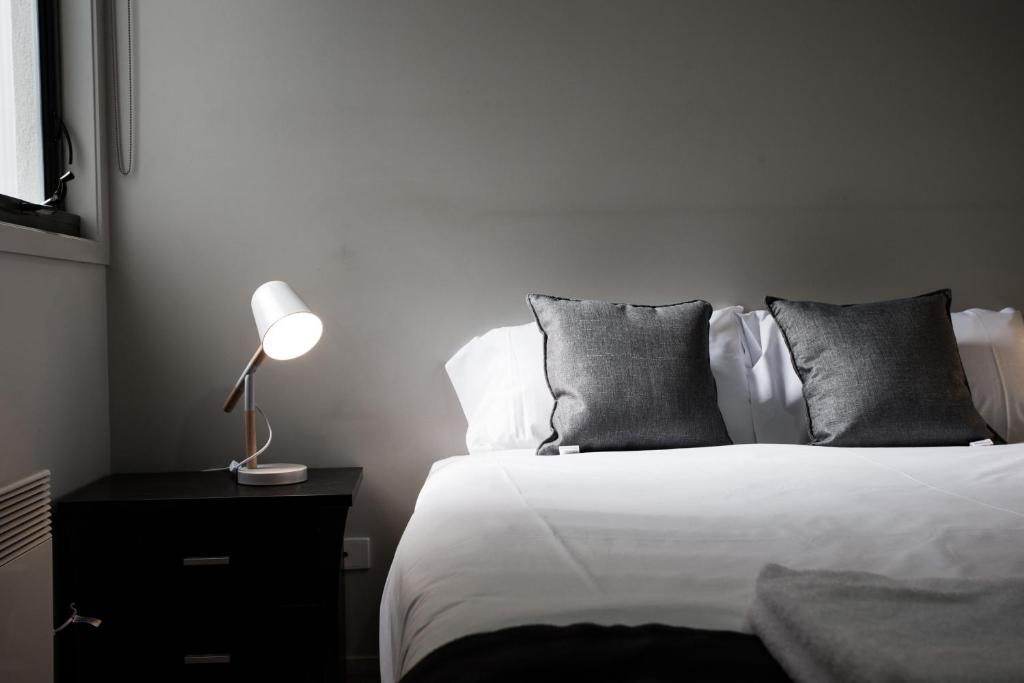 a bedroom with a bed and a lamp on a nightstand at ReadySet Apartments on Altona in Melbourne