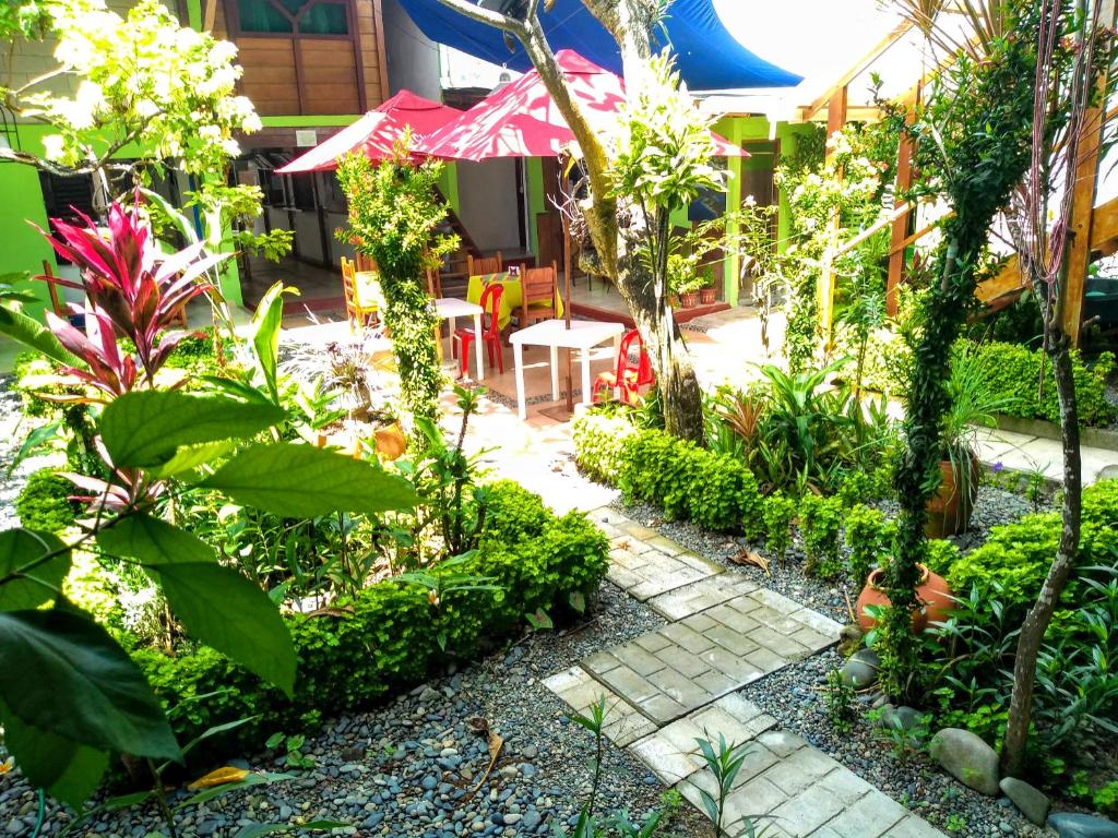 um jardim com plantas, uma mesa e um guarda-sol em Hostal Capurgana em Capurganá