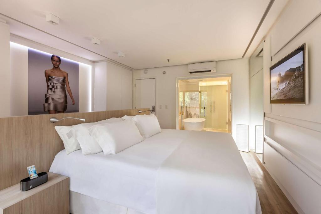 a bedroom with a large white bed with a woman standing on the wall at Bossa Nova Ipanema in Rio de Janeiro