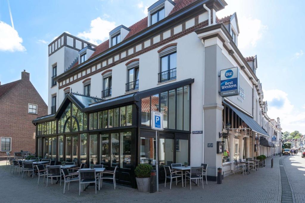 un bâtiment avec des tables et des chaises dans une rue dans l'établissement Best Western Hotel Baars, à Harderwijk