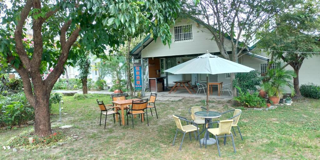 a patio with tables and chairs and an umbrella at Happy Come To B&B in Taiping