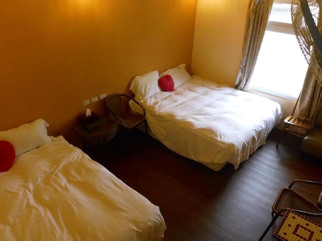 1 dormitorio con 2 camas y ventana en Liu Fu Shan Zhuang en Kenting