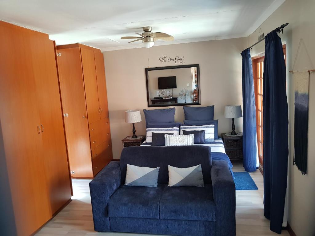 a living room with a blue couch and a bed at 4 You SELF-CATERING ACCOMMODATION in Centurion