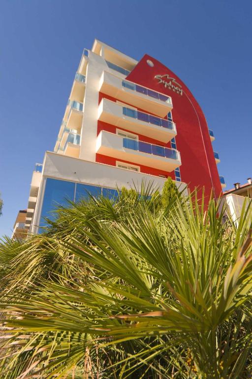 a tall building with a palm tree in front of it at Hotel Sydney in San Benedetto del Tronto