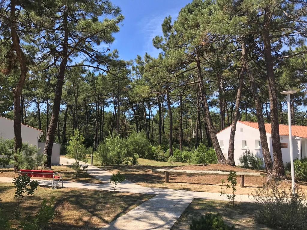 a garden with trees and a white building at Vent d'Eden Park Hôtel in Saint-Hilaire-de-Riez